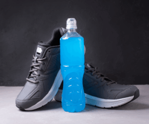 Bidón deportivos marcados con mililitros para controlar la hidratación durante un entrenamiento largo junto a unas zapatillas