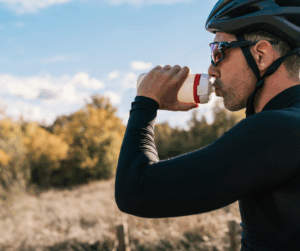 Ciclista hidratándose con bebida isotónica durante un entrenamiento para prevenir la deshidratación.