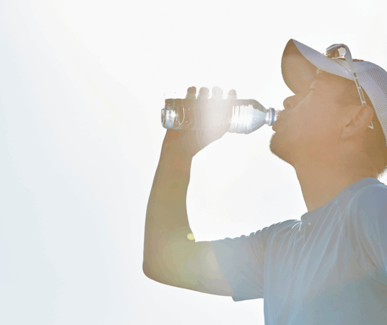 Corredor bebiendo agua durante el entrenamiento para prevenir la deshidratación deportiva.